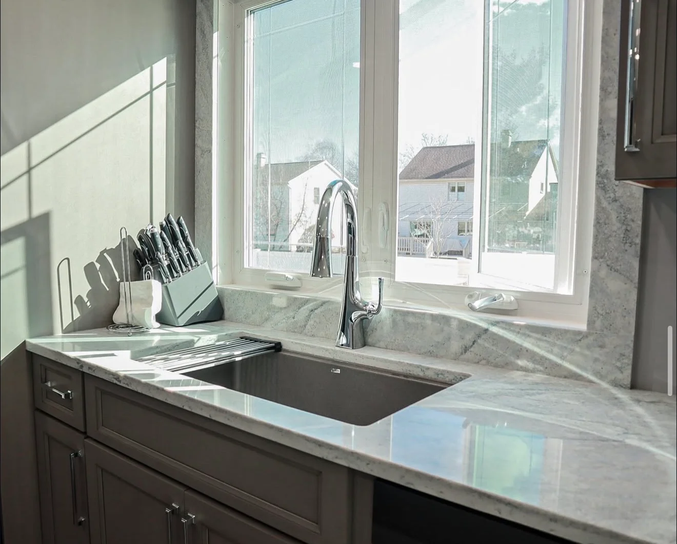 Light gray marble countertop with matching backsplash, undermount sink, and chrome faucet installation