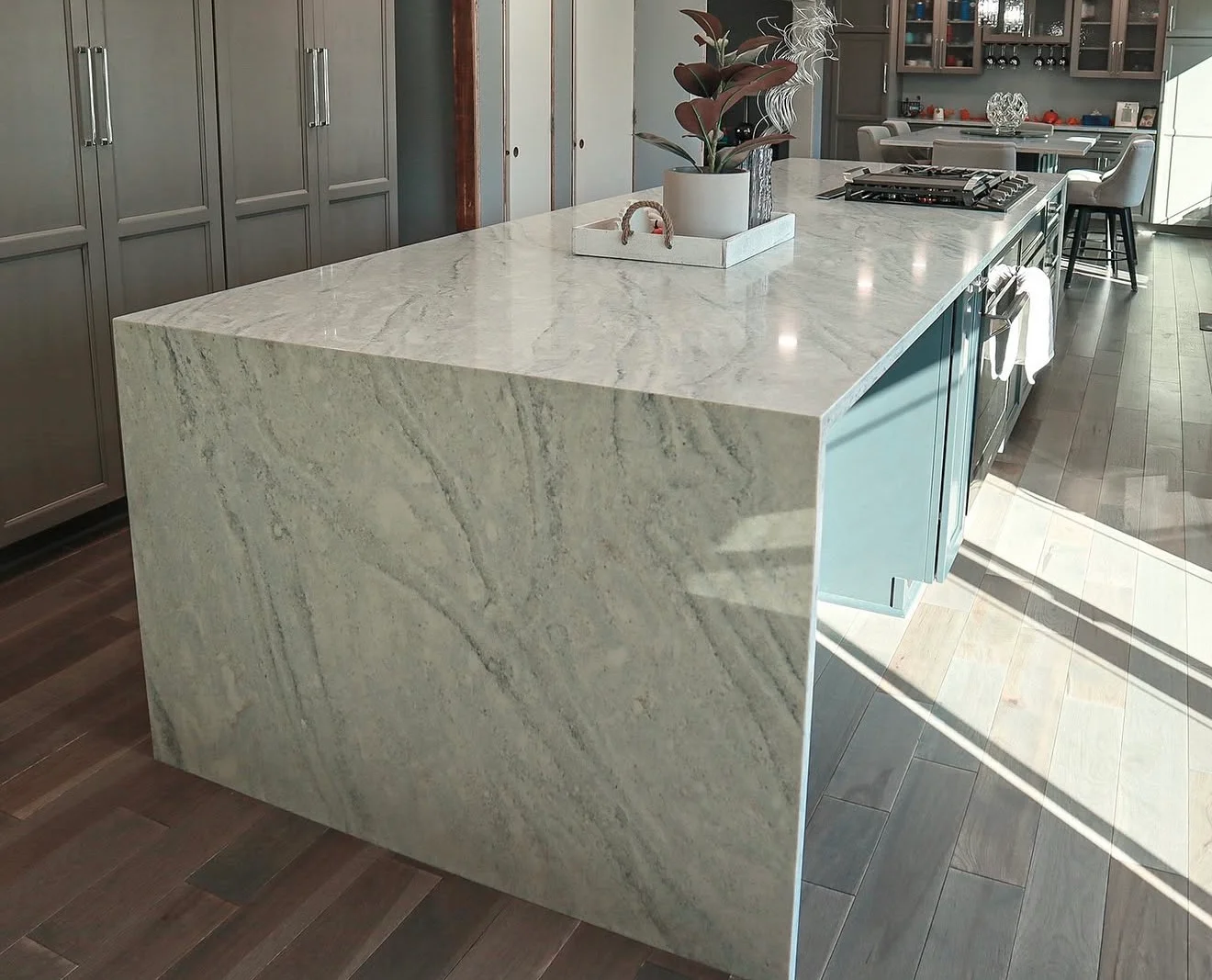 Polished marble island countertop with waterfall edge and gray veining in modern kitchen