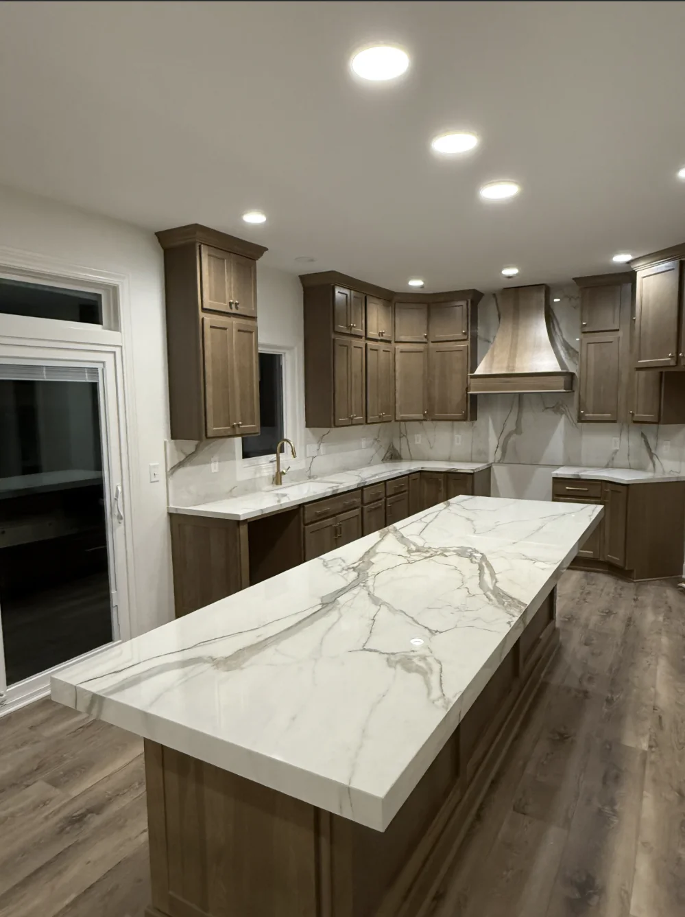White marble countertops with gray veining installed on dark wood cabinetry in kitchen with island