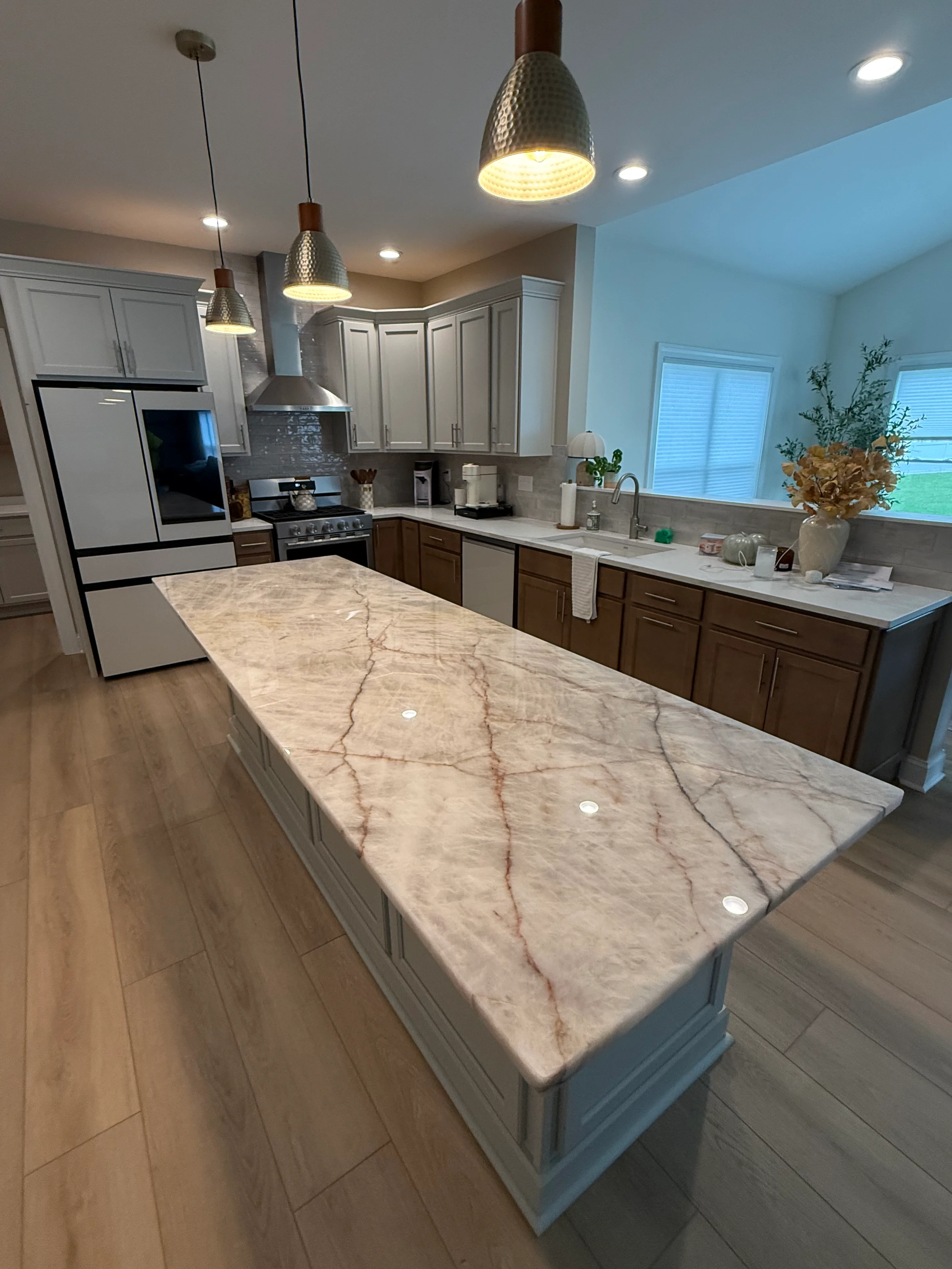 Marble island countertop with veining, white and dark wood cabinetry, stainless steel appliances