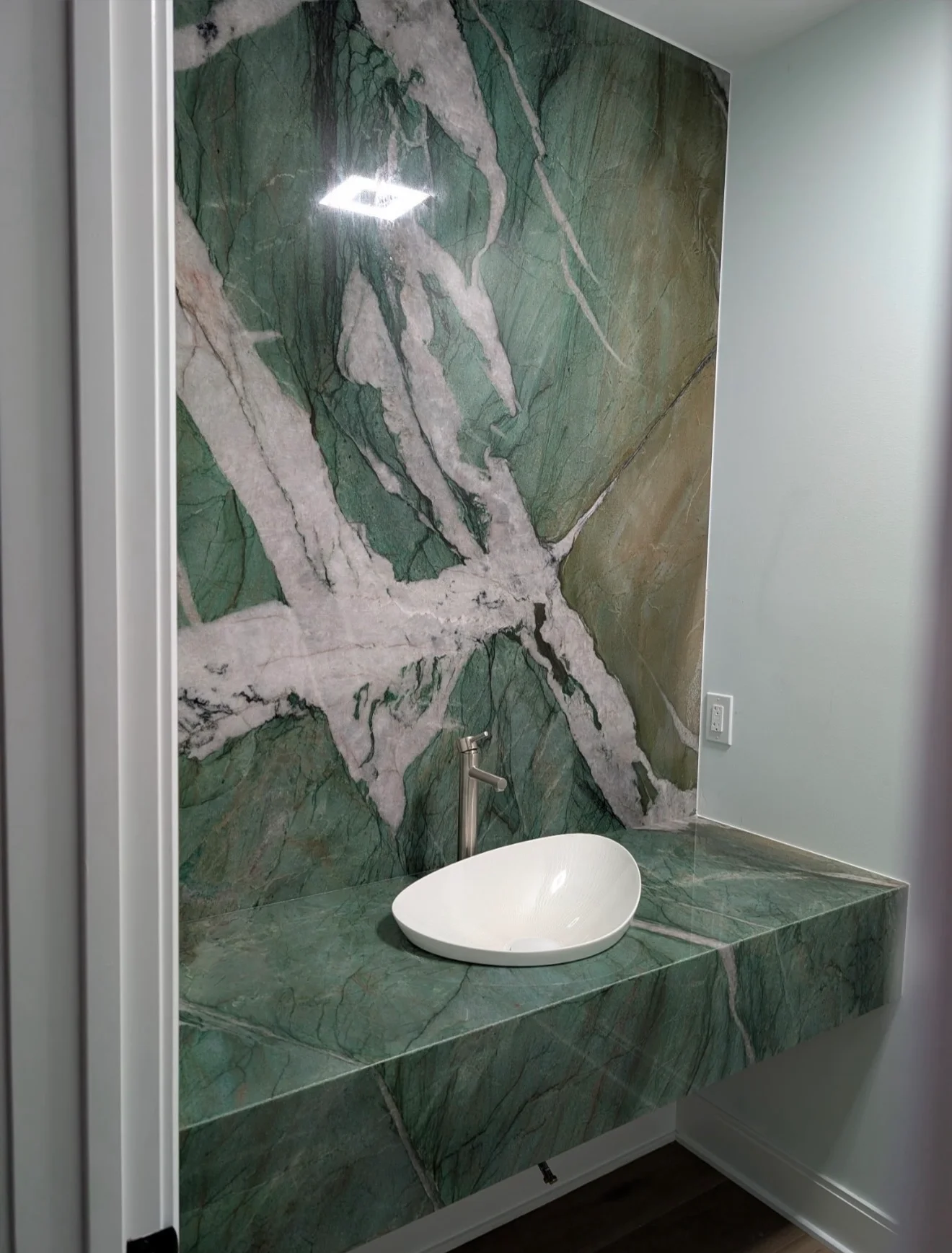 Green marble vanity countertop with white vessel sink and matching marble backsplash wall