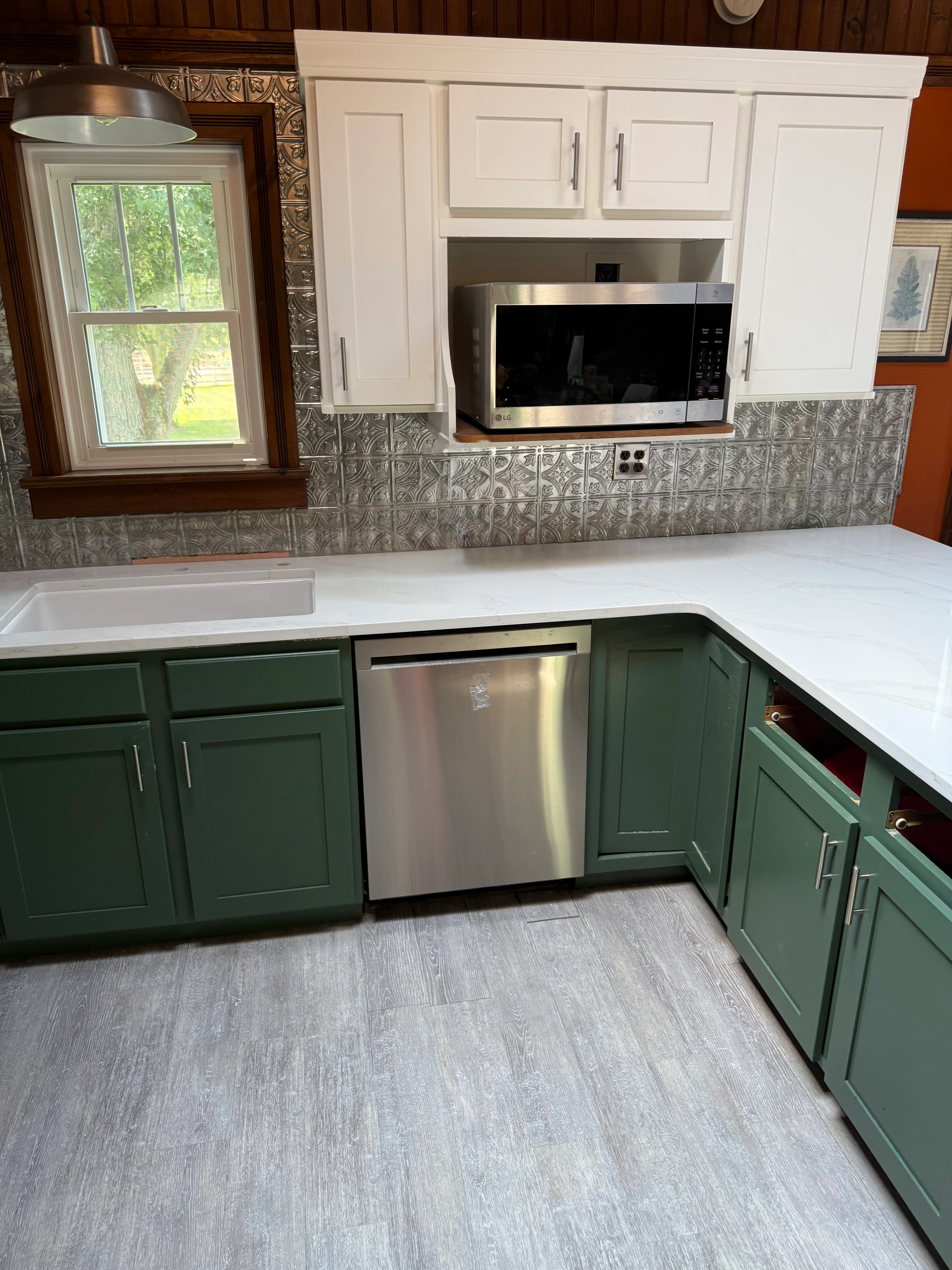 Kitchen with green and white cabinets, white quartz countertop, patterned tile backsplash, stainless steel appliances
