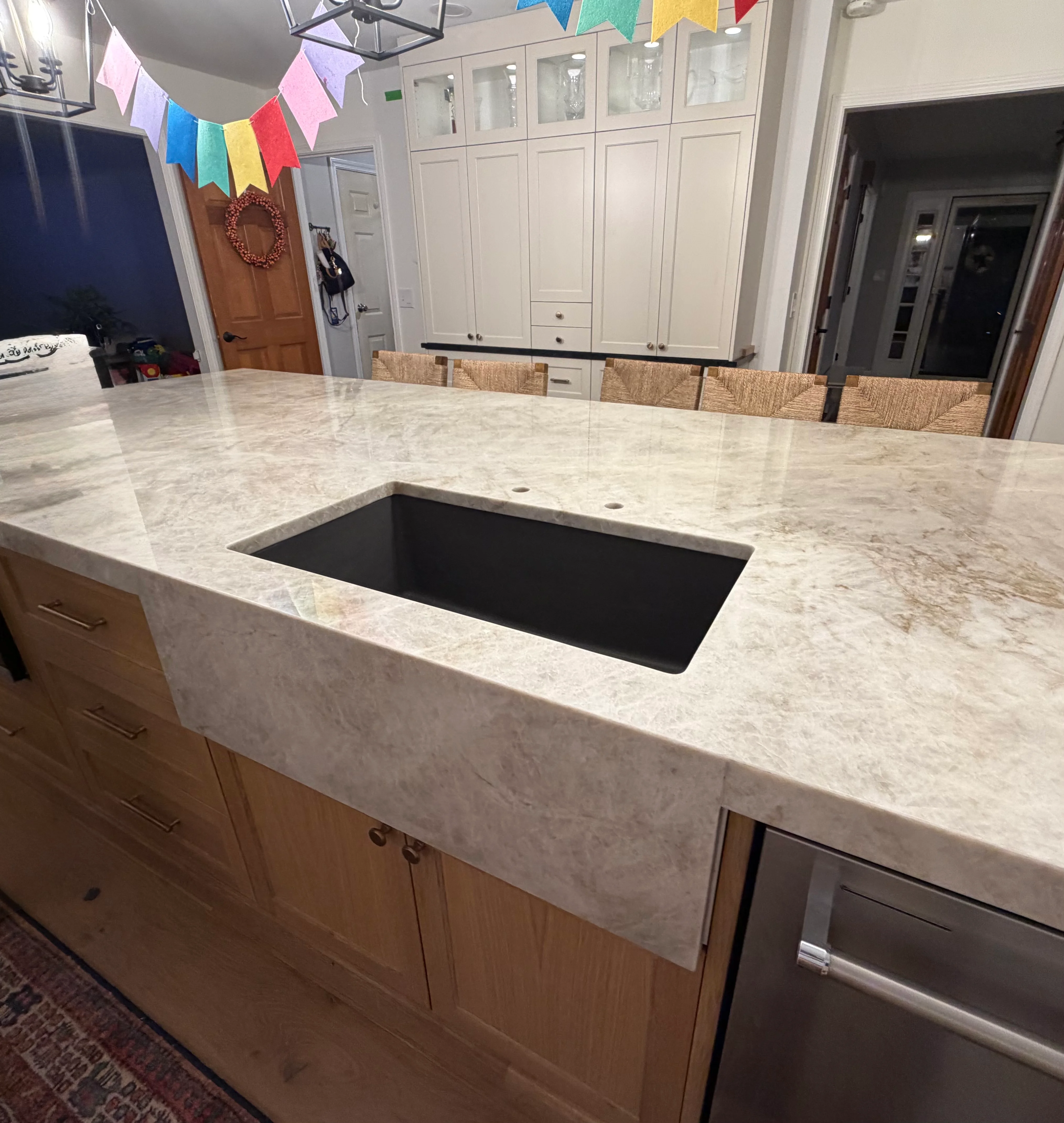 Light marble island countertop with rectangular black undermount sink and beveled edge
