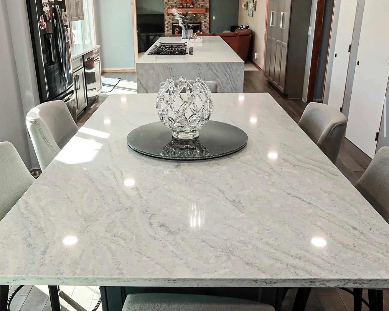 Polished white marble dining table and kitchen island with gray veining and integrated cooktop