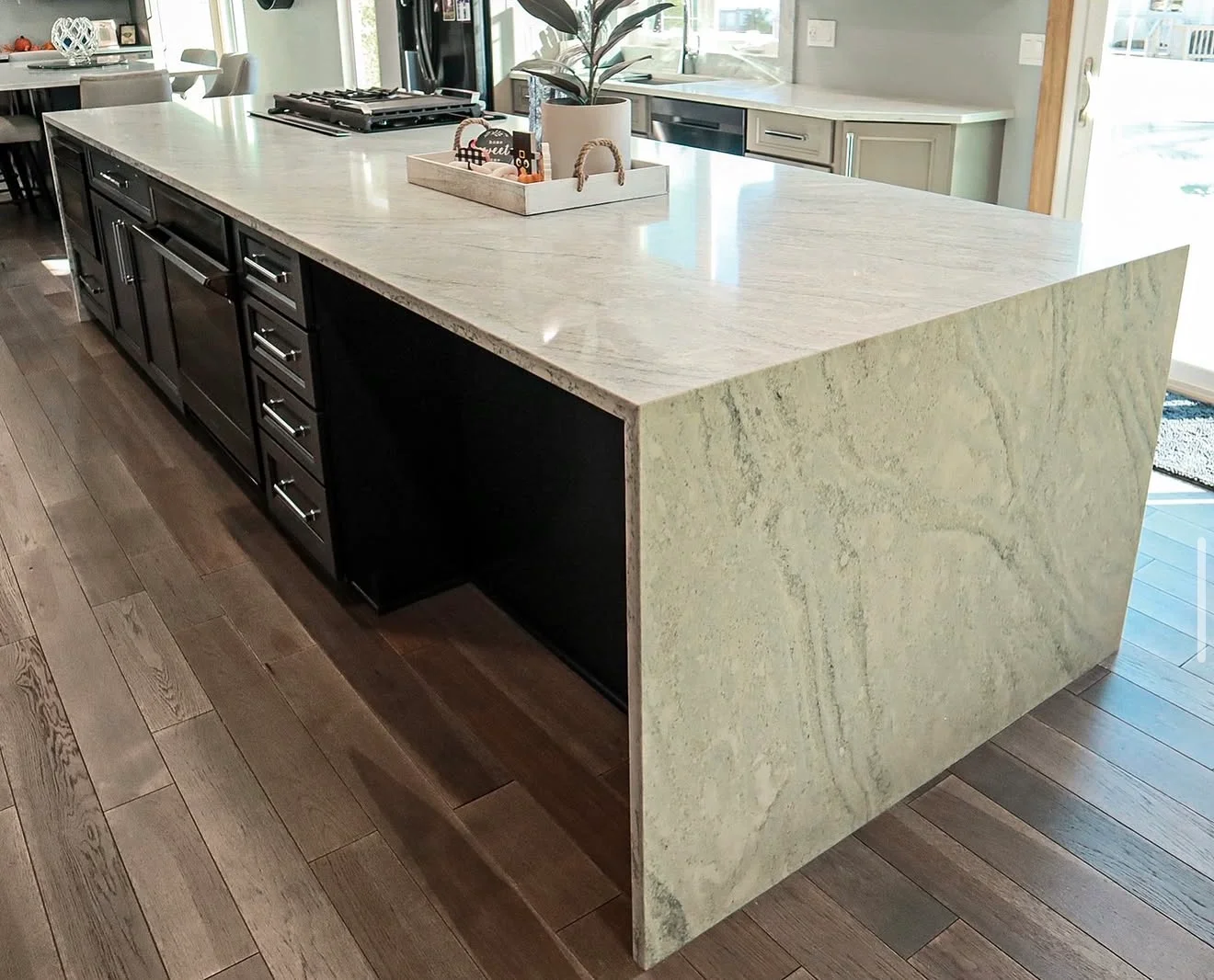 Light marble countertop with veining on black kitchen island cabinetry